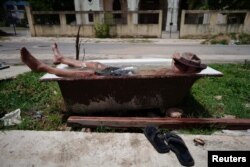 Retired painter Julio Rodriguez, 61, relaxes in a bathtub in front of his home in Havana, Cuba, July 19, 2023.