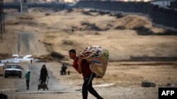 Palestinians carry their belongings as they prepare to flee Rafah in the southern Gaza Strip on May 13, 2024, amid the ongoing conflict between Israel and the Hamas militant group. 