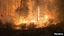 FILE - A fire burns close to the highway near Sorrento, British Columbia, Canada, on Aug. 18, 2023, in this screen grab obtained from social media video.