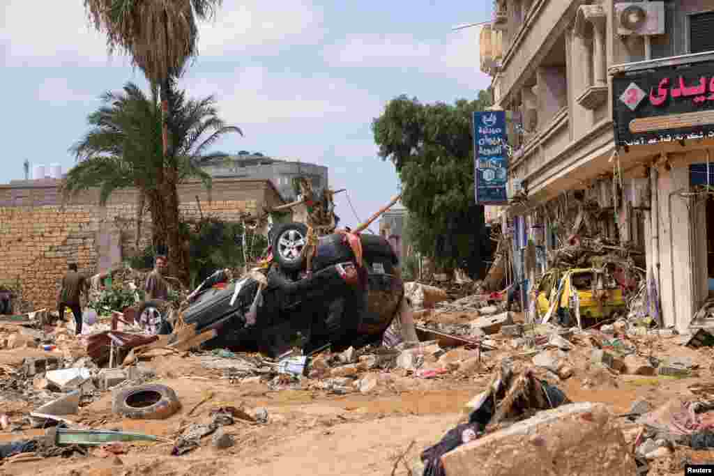 A man stands next to a damaged car in Derna after a powerful storm and heavy rainfall hit Libya, Sept. 12, 2023.
