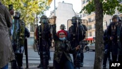 Mpinzani wa rais Paul Biya akiwainulia ngumi polisi wakati wa maandamano huko Paris, tarehe 22 2020. Picha na AFP.
