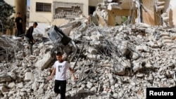 Anak-anak Palestina berjalan di tengah puing-puing bangunan yang rusak pasca serangan Israel di kamp Jenin di Tepi Barat yang diduduki Israel, 23 Mei 2024. (Foto: Reuters)