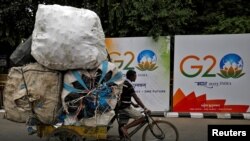 A man rides his trishaw past hoardings installed alongside a pavement ahead of the G20 Summit in New Delhi, Sept. 6, 2023. 
