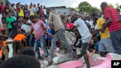 People carry an injured person away from a home that collapsed after an earthquake in Jeremie, Haiti, June 6, 2023. 