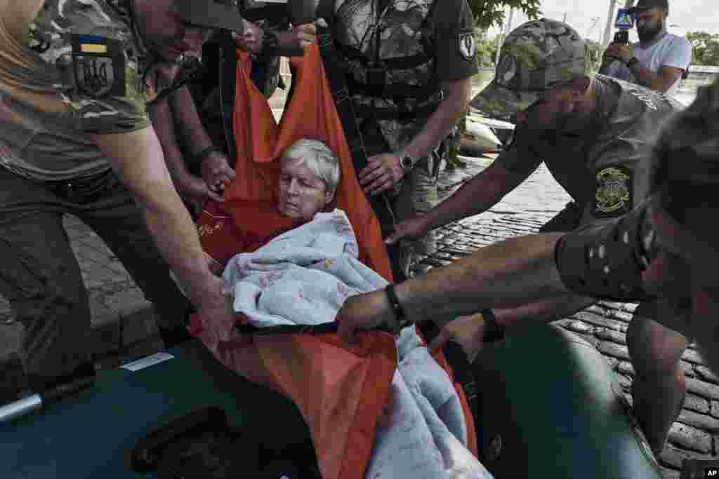 Emergency workers evacuate an elderly resident on a rubber boat from a flooded neighborhood in Kherson, Ukraine, June 7, 2023. 