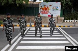 Central Reserve Police Force personnel patrol a road next to a hoarding ahead of the G20 Summit in New Delhi, Sept. 6, 2023.