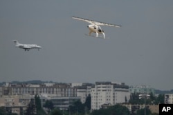 The Volocopter 2X, an electric vertical takeoff and landing multicopter, right, performs a demonstration flight during the Paris Air Show in Le Bourget, north of Paris, France, Monday, June 19, 2023. (AP Photo/Lewis Joly)