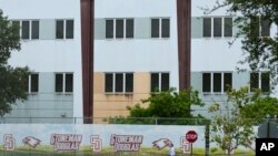 FILE - A security agent walks alongside a barrier surrounding Marjory Stoneman Douglas High School in Parkland, Florida, July 5, 2023. 