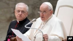 Pope Francis flanked by Father Leonardo Sapienza, left, delivers his speech during his weekly general audience in the Paul VI hall at The Vatican, Aug. 30, 2023.
