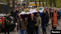 Local residents carry the caskets of two children, Sofia and Kyrylo, who were killed on Friday by a Russian missile strike, in the city of Uman, Cherkasy region, Ukraine, April 30, 2023.