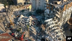 FILE - Rescue teams search for people as cranes remove debris from destroyed buildings in Antakya, southeastern Turkey, Feb. 10, 2023.