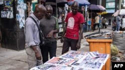 Men look at newspaper headlines in Monrovia, Liberia, on Oct. 11, 2023, after Liberians voted in their general elections.