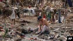 A man washes his clothes in a stream near debris left over after flooding devastated the village of Nanxinfang on the outskirts of Beijing on Aug. 4, 2023. 