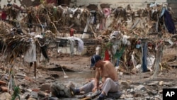 4일 중국 베이징 외곽의 난신팡 마을에서 한 주민이 홍수로 인한 잔해가 쌓인 개울에서 옷을 빨고 있다. 