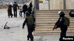 FILE - Palestinians look at Israeli border police after they attended Friday prayer in the West Bank city of Hebron Nov. 6, 2015.