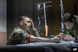 A medic gives first aid to a wounded Ukrainian soldier near Bakhmut, the site of the heaviest battles with the Russian troops, Donetsk region, Ukraine, Feb. 27, 2023.