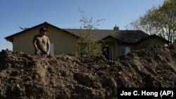 Earl Gomes, 33, stands for a photo outside his home with a berm he built to protect the property from possible flooding of the Kings River in the Island District of Lemoore, Calif., Thursday, April 20, 2023. (AP Photo/Jae C. Hong)