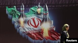 이란 수도 테헤란에서 미사일이 그려진 반이스라엘 현수막 앞을 지나고 있는 한 여성 (자료사진)