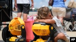 FILE - Braxton Hicks, 7, of Livingston, Texas, holds his face to a portable fan to cool off during the DYB, formerly Dixie Youth Baseball, Little League tournament in Ruston, La., Aug. 9, 2023.