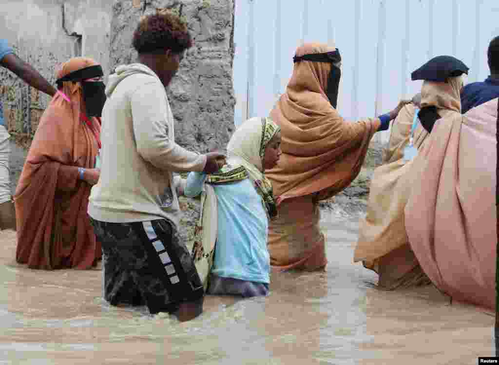 People wade through flood waters on a street in Wadajir district of Mogadishu, Somalia.