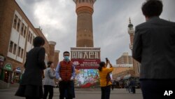 FILE - Tourists take photos near a tower at the International Grand Bazaar in Urumqi in western China's Xinjiang Uyghur Autonomous Region, as seen during a government-organized trip for foreign journalists on April 21, 2021.