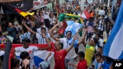 Penggemar sepak bola mengibarkan bendera negara peserta saat parade jelang kick-off Piala Dunia FIFA Qatar, di Desa Pambusuang, Sulawesi Barat, Minggu, 20 November 2022. (Foto: AP)