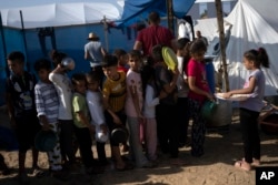 Children wait in line for a food distribution in a displaced tent camp, in Khan Younis, southern Gaza Strip, Oct. 25, 2023.