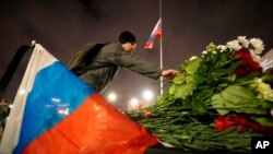 Seorang lelaki meletakkan bunga untuk mengenang para korban serangan di Moskow di St. Petersburg, Rusia, Sabtu, 23 Maret 2024. (Foto: AP)