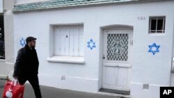 FILE - A man walks by Stars of David tagged on a wall in Paris, on Oct. 31, 2023.