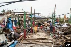 Warga berjalan melewati bangunan yang rusak akibat Topan Mocha di Kotapraja Sittwe, Negara Bagian Rakhine, Myanmar, 16 Mei 2023. (Foto: AP).