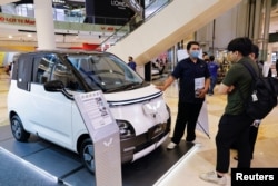 Seorang penjual menjelaskan mengenai mobil listrik kepada pengunjung di sebuah mal di Jakarta, 5 Februari 2023. (Foto: Willy Kurniawan/Reuters)