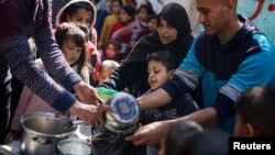Palestinian children wait to receive food prepared by a charity kitchen amid shortages of food supplies, as the conflict between Israel and Hamas continues, in Rafah, in the southern Gaza Strip, March 5, 2024.