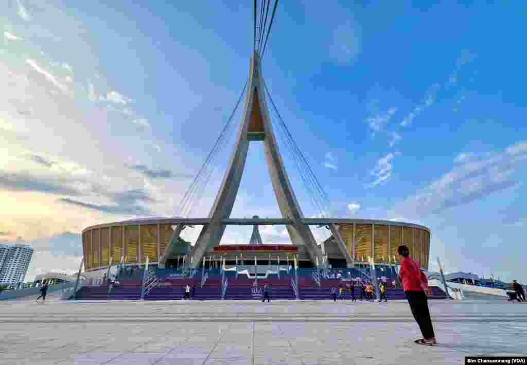 ស្រ្តី​ម្នាក់​ឈរ​មើល​ទៅ​ពហុ​កីឡ​ដ្ឋាន​មរតក​តេជា ក្នុង​រាជធានី​ភ្នំពេញ នៅ​ថ្ងៃទី១៣ ខែឧសភា ឆ្នាំ២០២៣។ (ស៊ឹម ចាន់សំណាង/វីអូអេ)