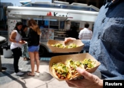 لاس اینجلس میں لوگ ایک فود ٹرک سے ٹاکوز خرید رہے ہیں۔ فائل فوٹو