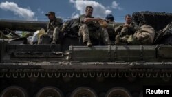 Ukrainian servicemen sit atop a military vehicle, amid Russia's attack on Ukraine, near the Russian border in Ukraine's Sumy region, Aug. 11, 2024.