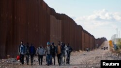 FiLE - Migran berjalan di sepanjang perbatasan AS-Meksiko setelah menyeberang dari Meksiko dekat Lukeville, Arizona, AS, 24 Desember 2023. (REUTERS/Rebecca Noble)