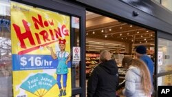 FILE - A hiring sign is displayed at a grocery store in Arlington Heights, Illinois,, Jan. 13, 2023. A strong job market has helped fuel the inflation pressures that have led the Federal Reserve to keep raising interest rates.