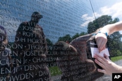 FILE - A visitor makes a rubbing of the name of a fallen soldiers at Vietnam Veterans Memorial on May 29, 2022. (AP Photo/Jose Luis Magana)