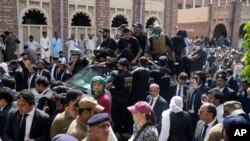 Security escorts a vehicle carrying Pakistan's former Prime Minister Imran Khan and his wife, Bushra Bibi, after their court appearance in Lahore, Pakistan, May 15, 2023.