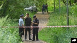 Police and investigators stand at the side of the wreckage of the drone felled near the Karamyshevskaya embankment in Moscow, Aug. 11, 2023.