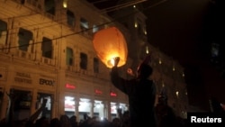 FILE - A man prepares to release a home-made paper sky lantern during New Year celebrations in Lahore, Pakistan, Dec. 31, 2015. 