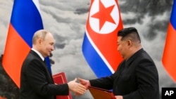 Russian President Vladimir Putin, left, and North Korea's leader Kim Jong Un exchange documents during a signing ceremony of the new partnership in Pyongyang, North Korea, June 19, 2024.