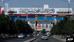 FILE - Commuters drive under a banner placed by Taliban authorities, near the Kabul airport, Aug. 30, 2022. Taliban allegedly barred 100 female students from leaving Afghanistan for the United Arab Emirates in August 2023, where they were to enroll in university studies. 