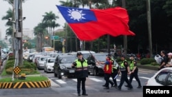 台湾警察护送一名举着台湾旗帜的男子走过台北街头。（2024年5月24日）