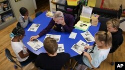 Richard Evans, a teacher at Hyde Park Elementary School, helps Ke'Arrah Jessie sound out a word during a reading circle in class on Thursday, Oct. 20, 2022, in Niagara Falls, N.Y. (AP Photo/Joshua Bessex)