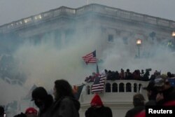 FILE - Police clear the U.S. Capitol Building with tear gas as supporters of President Donald Trump gather outside in Washington on Jan. 6, 2021.