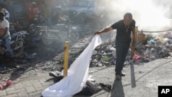 A person lifts a sheet to look at the identity of a body lying on the ground after an overnight shooting in the Petion Ville neighborhood of Port-au-Prince, Haiti, March 18, 2024.