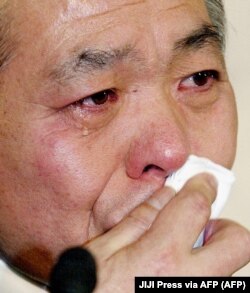 Anggota parlemen LDP yang berkuasa di Jepang, Muneo Suzuki, menitikkan air mata saat konferensi pers di markas besar LDP di Tokyo, 15 Maret 2002, mengumumkan pengunduran dirinya dari partai tersebut. (Foto: JIJI Press via AFP)