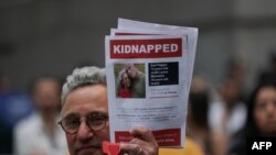 A man holds a picture of Gad Haggai and Judith Lynne Weinstein, who were kidnapped from Israel on October 7, during a rally in New York, Oct. 26, 2023. Haggai was killed on the day of the attack, his kibbutz community said Friday. 