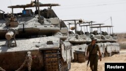 Seorang tentara Israel berjalan di dekat sekumpulan tank yang diparkir di dekat wilayah perbatasan antara Israel selatan dan Gaza pada 28 April 2024. (Foto: Reuters/Amir Cohen)